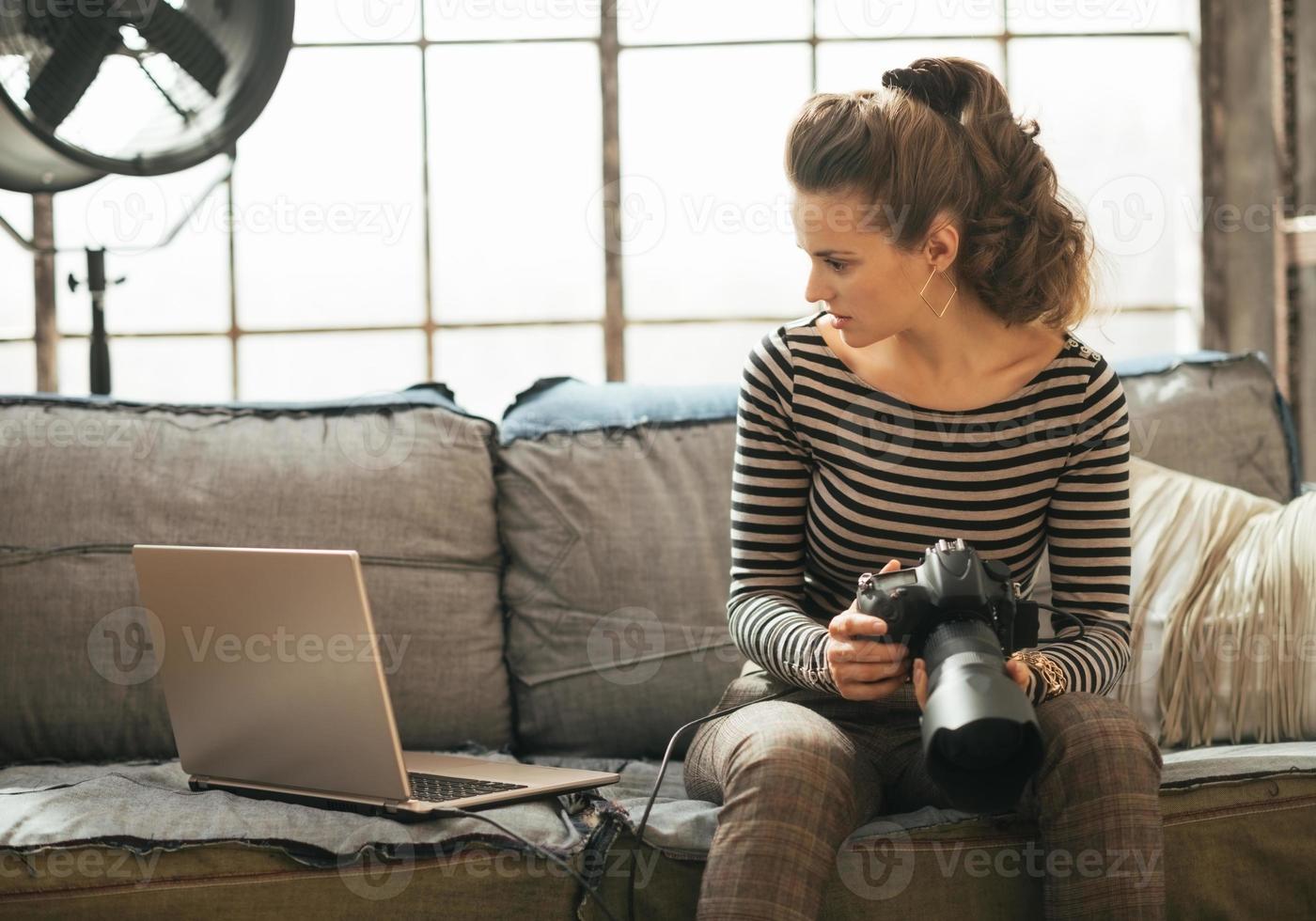 jonge vrouw met moderne dslr fotocamera met behulp van laptop foto