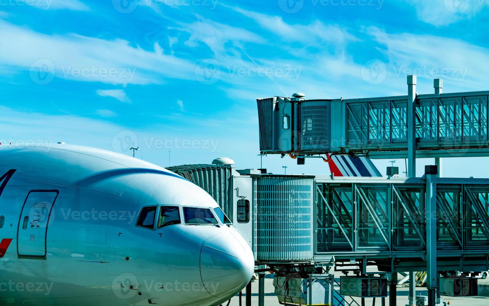 commerciële luchtvaartmaatschappij geparkeerd bij jet bridge voor het opstijgen van passagiers op de luchthaven. vliegtuigen passagiers instapbrug aangemeerd met blauwe lucht en witte wolken. vertrekvlucht van internationale luchtvaartmaatschappij. foto