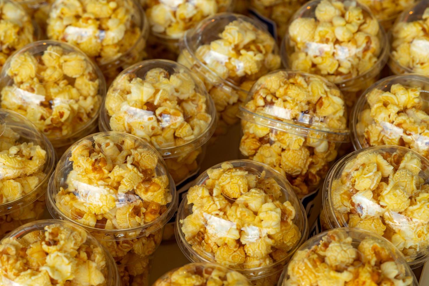 popcorn in een plastic beker is prachtig geplaatst. ongezond voedsel of snackconcept. lekkere zoute popcorn. koolhydraten eten. junk food. popcorn op plastic glas te koop of doneer voor liefdadigheidsevenement. foto