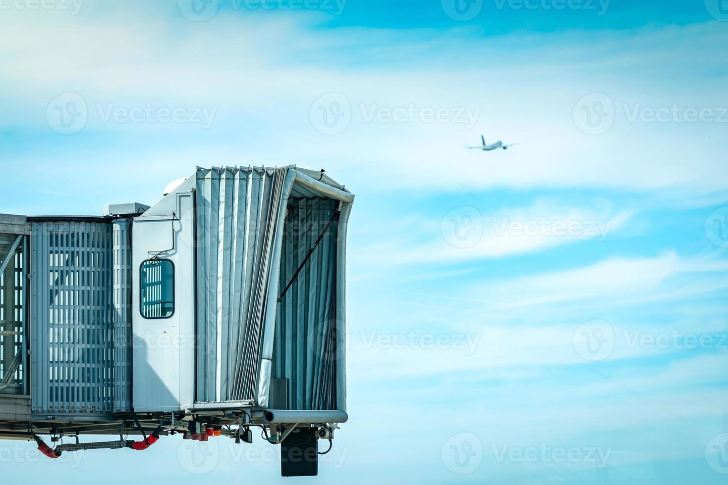 straalbrug na commerciële luchtvaartmaatschappij opstijgen op de luchthaven en het vliegtuig vliegen in de blauwe lucht en witte wolken. passagiersbrug voor vliegtuigen aangemeerd. vertrekvlucht van internationale luchtvaartmaatschappij. foto