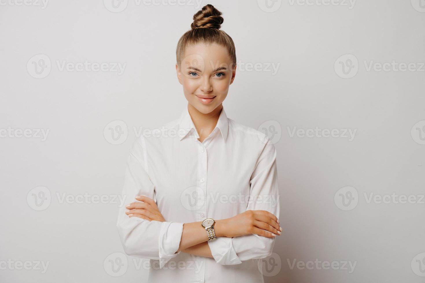 zelfverzekerde vrouwelijke manager in wit overhemd met gekruiste armen foto