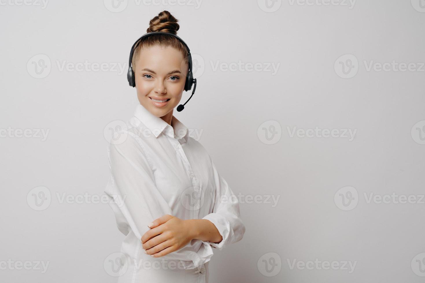 vrouwelijke callcenteragent met zwarte headset en gekruiste armen foto