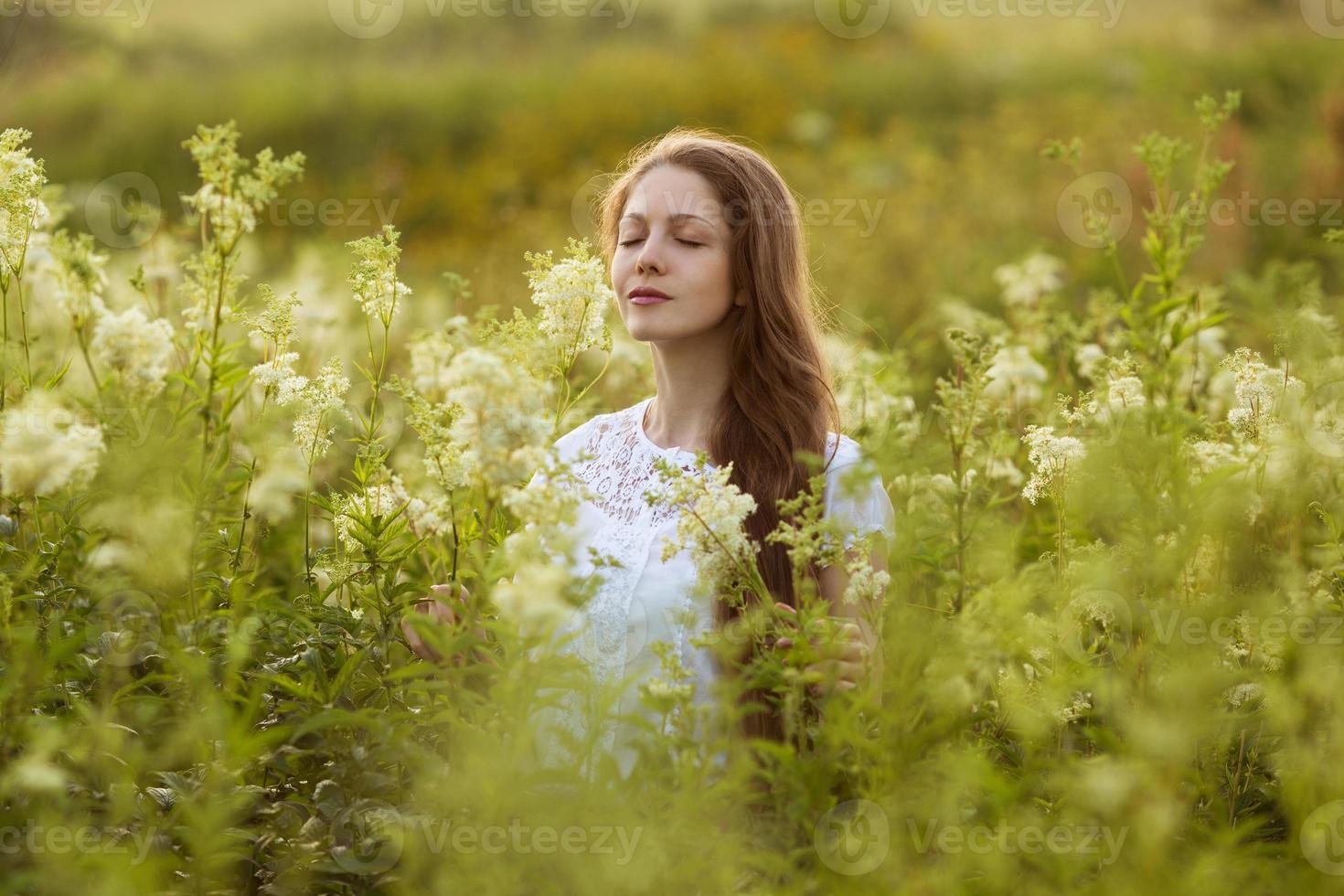 gelukkige vrouw met gesloten ogen onder de wilde bloemen foto