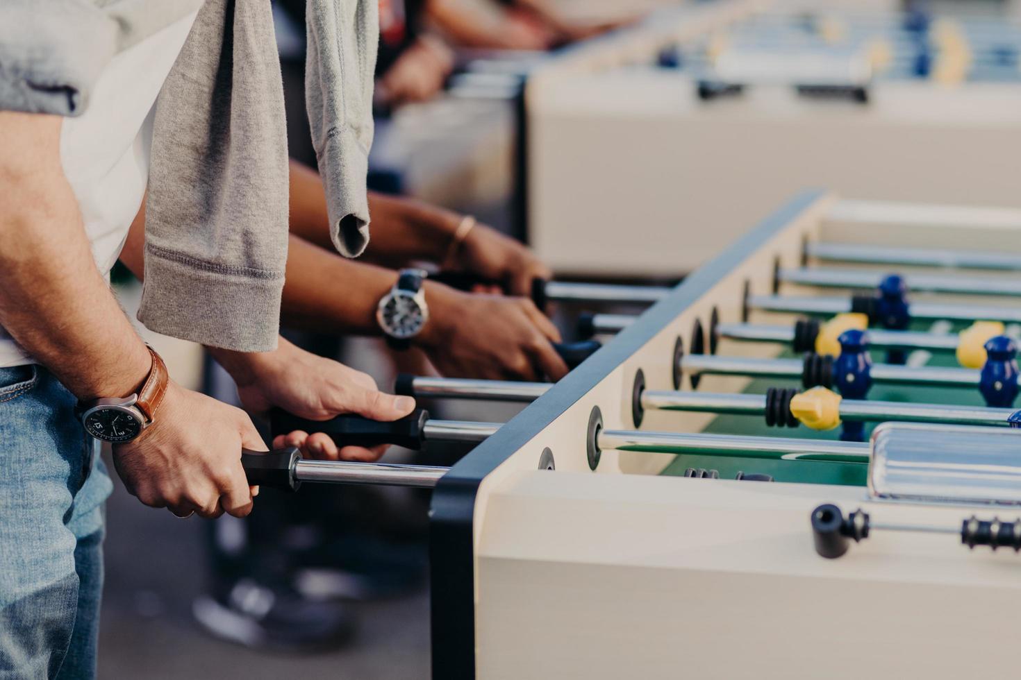 mensen, lifestyle, gokken en recreatie concept. actieve mannelijke speler geniet van vrije tijd terwijl hij samen tafelvoetbal speelt. mensen hebben kicker match foto