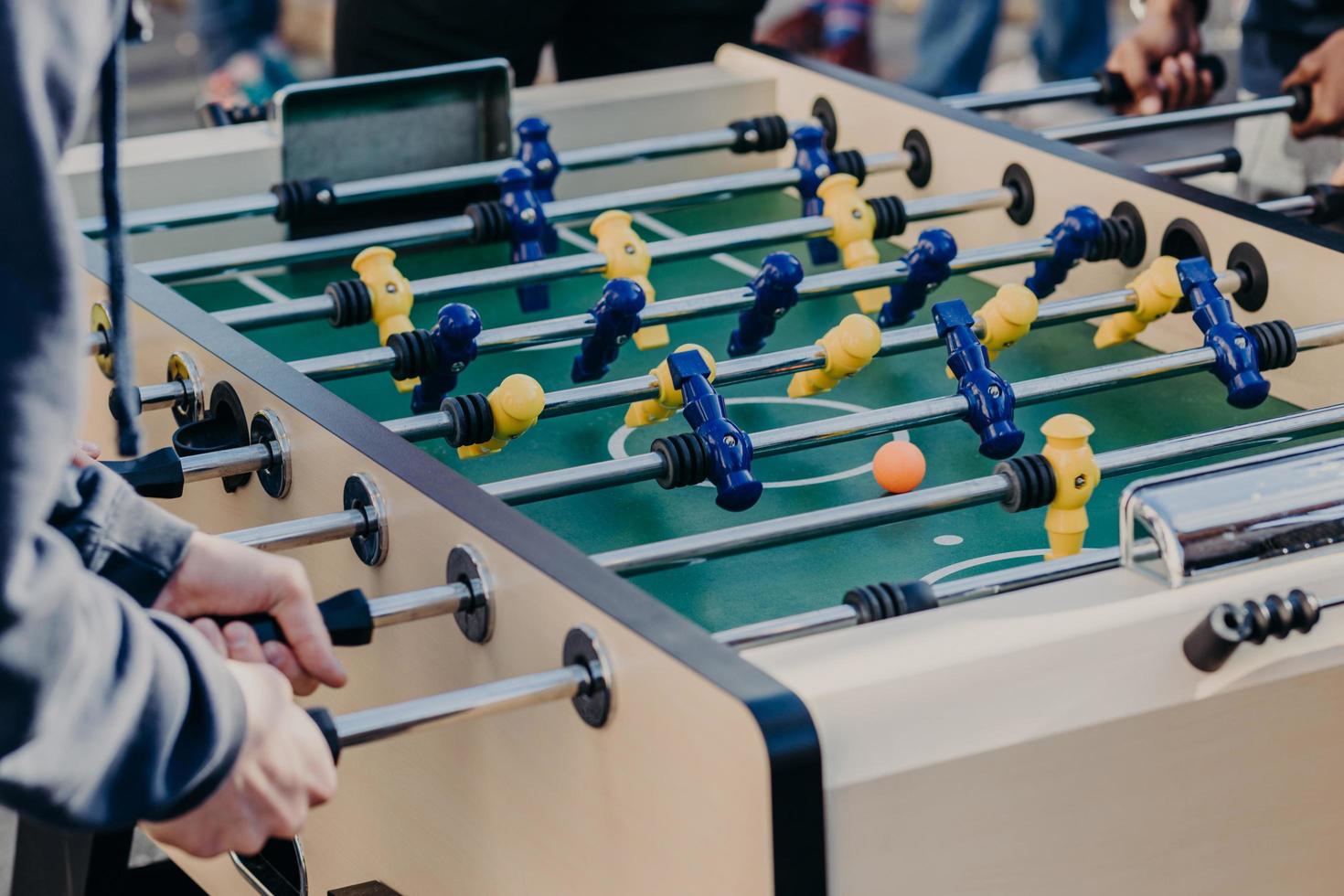 mannelijke vrienden hebben samen een onvergetelijke tijd, spelen tafelvoetbal of kricker, hebben plezier, willen de overwinning behalen. close-up beeld van plastic kleurrijke spelers foto