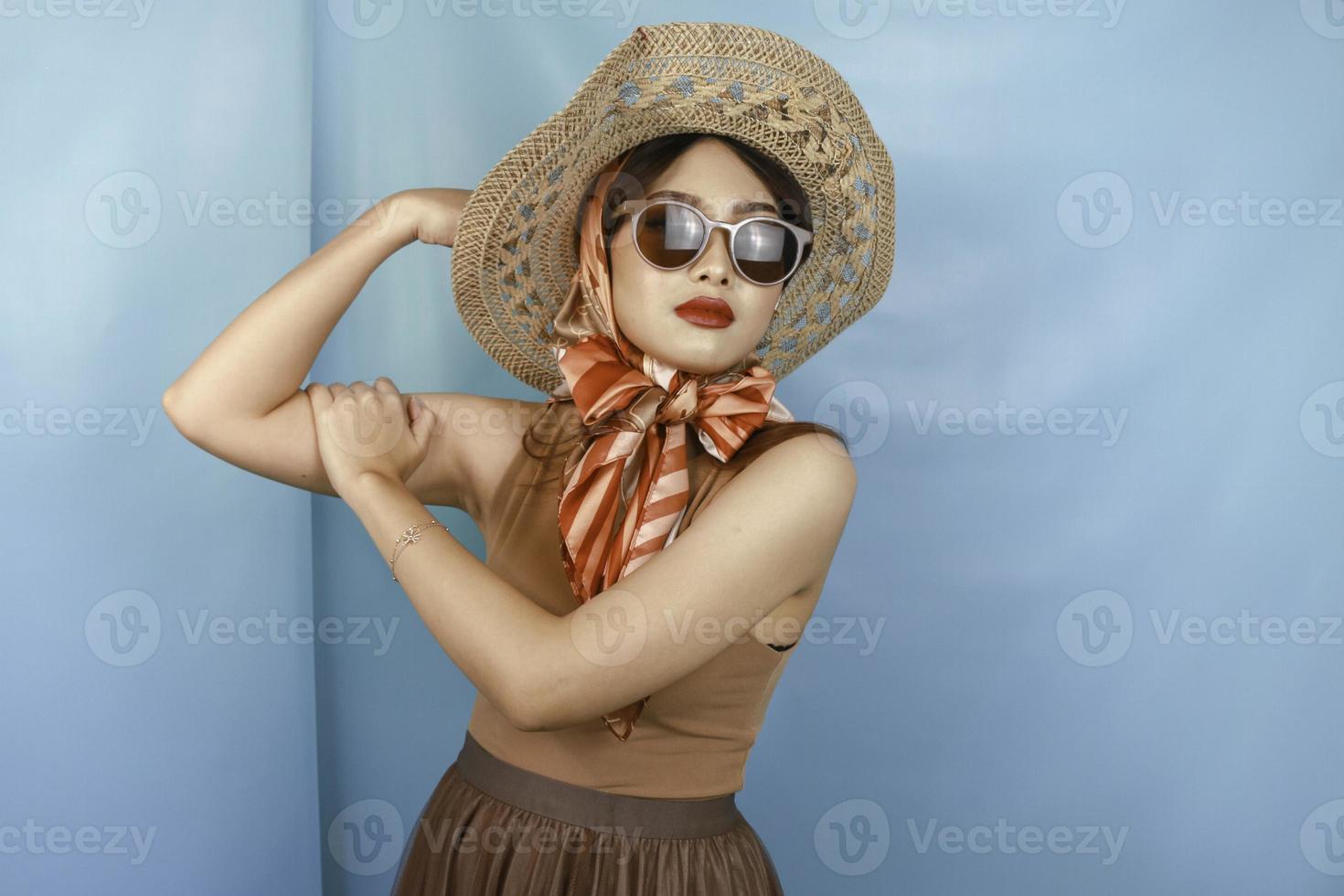 jonge Aziatische sterke vrouw toont haar biceps geïsoleerd door een blauwe achtergrond foto
