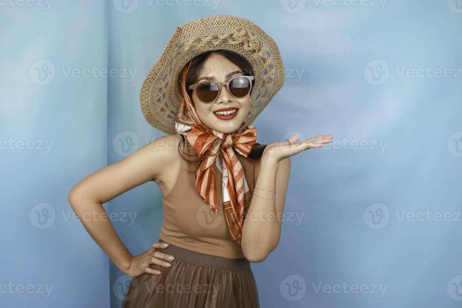 jonge Aziatische gelukkige vrouw geïsoleerd door een blauwe achtergrond die kopieerruimte aan de zijkant wijst. foto