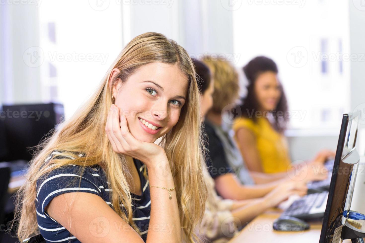 student die bij camera in computerklasse glimlacht foto