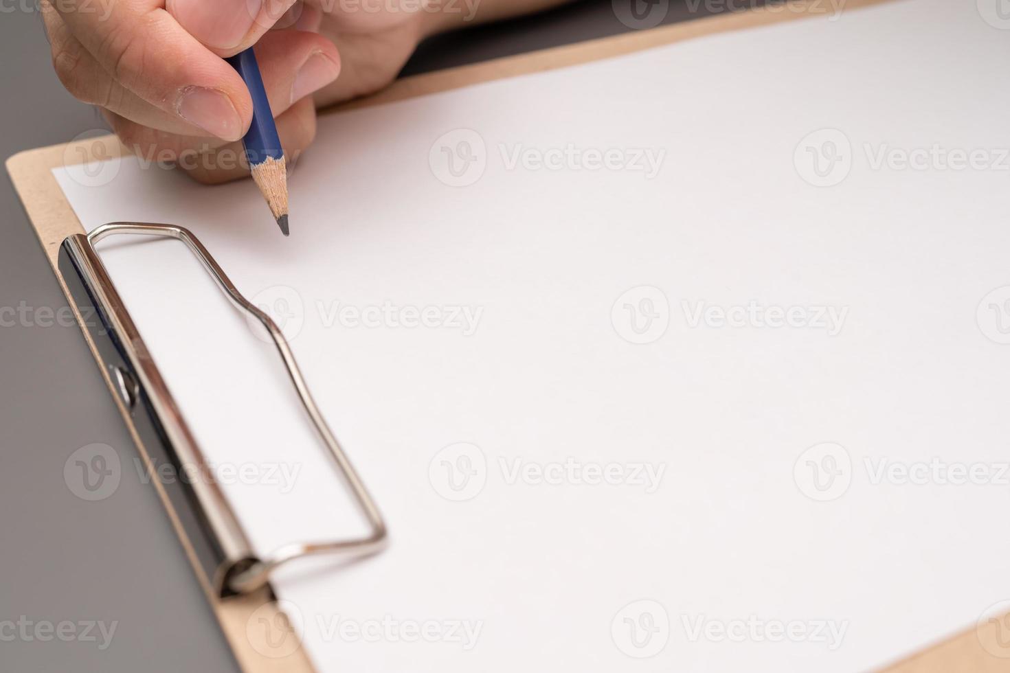 hand schrijven op klembord. briefpapier. schrijf een notitie op lege blanco met een potlood foto