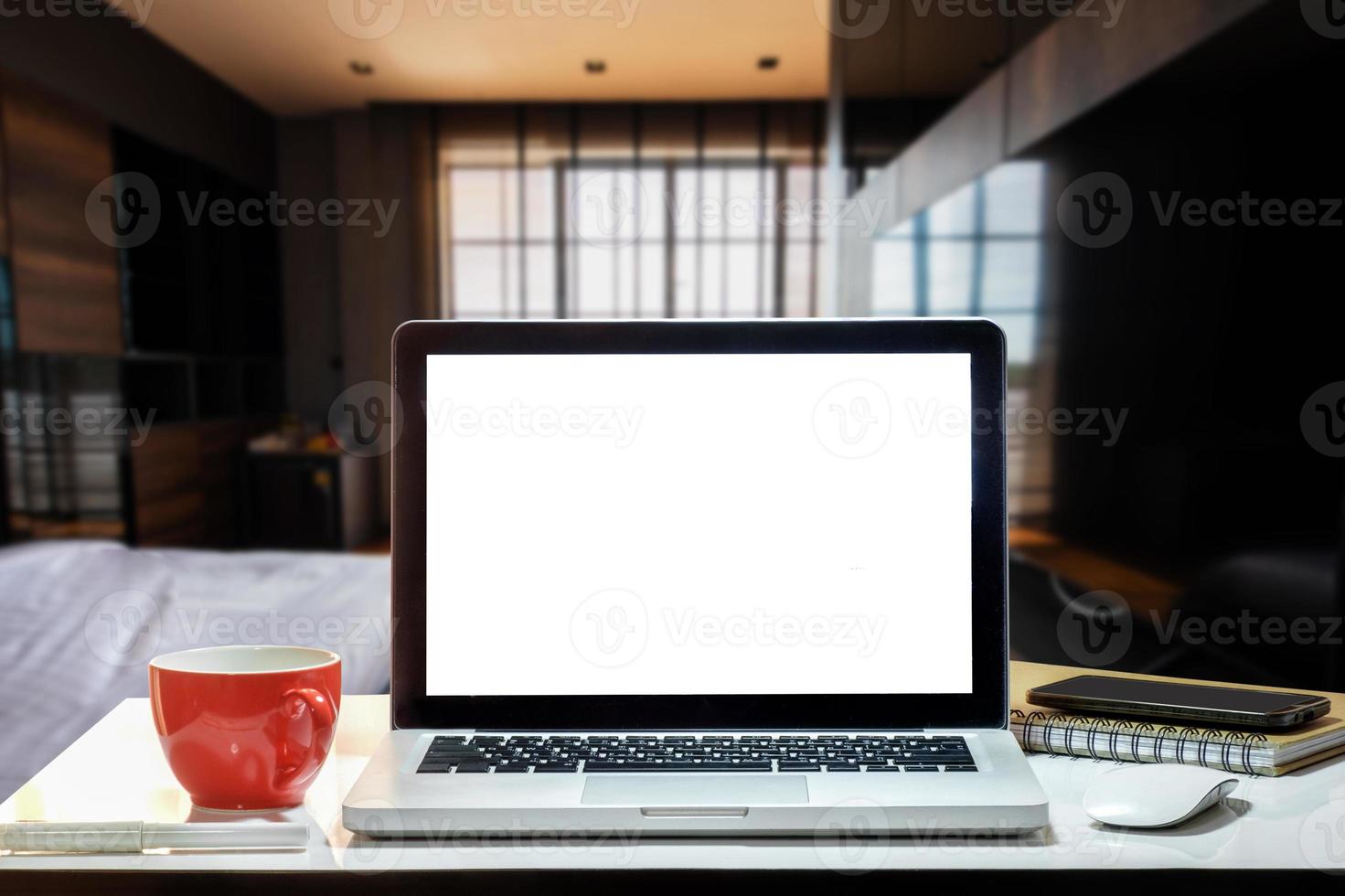 vooraanzicht van beker en laptop, smartphone en tablet op tafel op kantoor en achtergrond in de coffeeshop foto