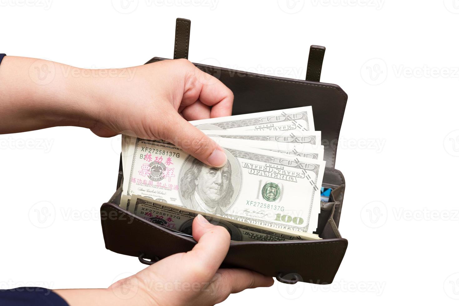 de hand van de vrouw houdt een paar honderd-dollarbiljetten en een portemonnee vast op een geïsoleerde of uitgesneden achtergrond met een uitknippad. Chinese die op de bankbiljetten verschijnen, zijn replica's van bankbiljetten om te filmen. foto
