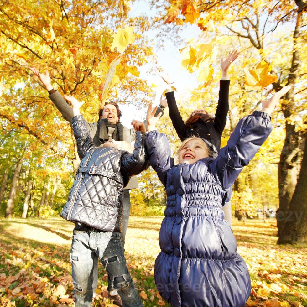 familie spelen met herfstbladeren foto
