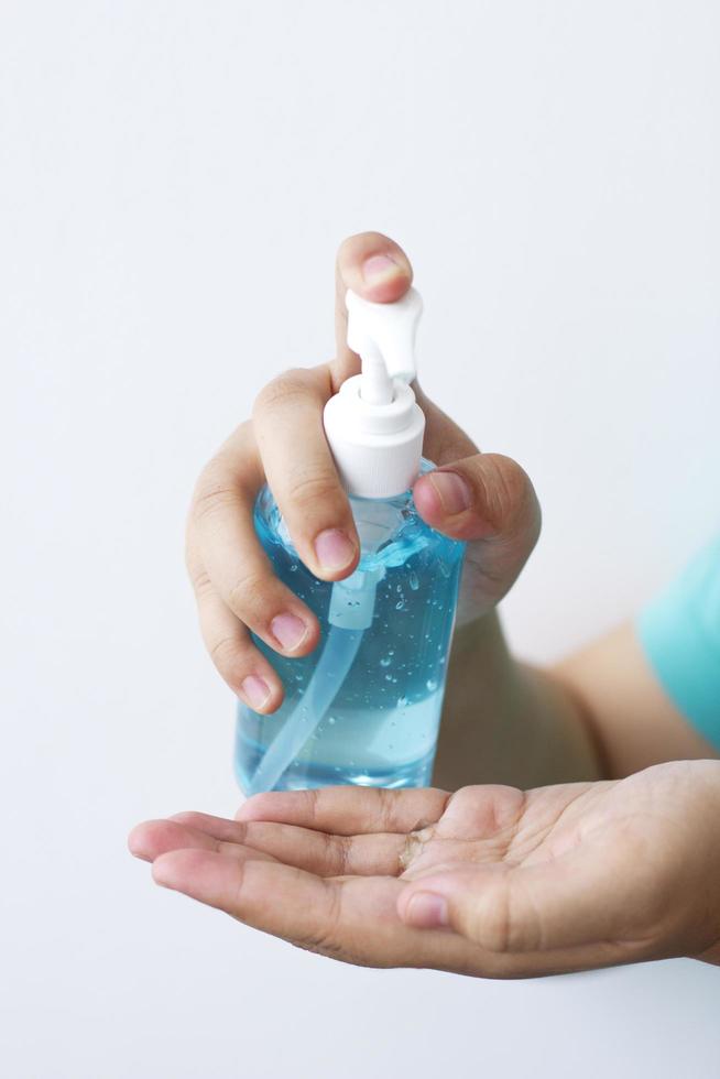 vrouw die op alcoholgel drukt die bacteriën en virussen op witte achtergrond schoonmaakt. foto