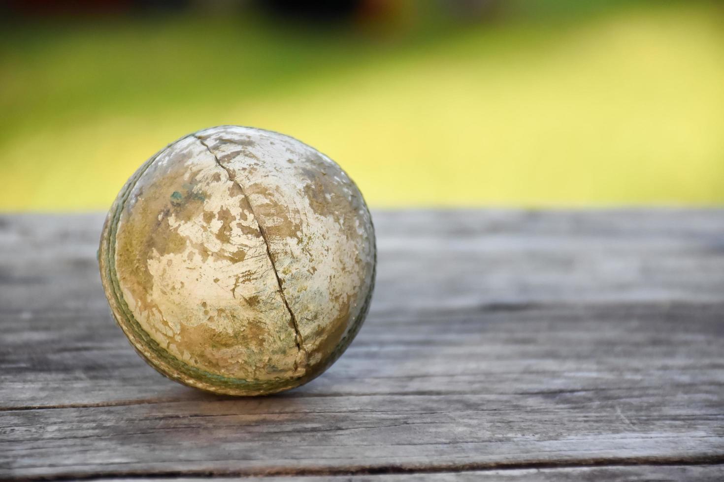 oude trainingscricket-sportuitrusting op donkere vloer, leren bal, wickets, helm en houten vleermuis, zachte en selectieve focus, traditionele cricketsportliefhebbers over de hele wereld. foto