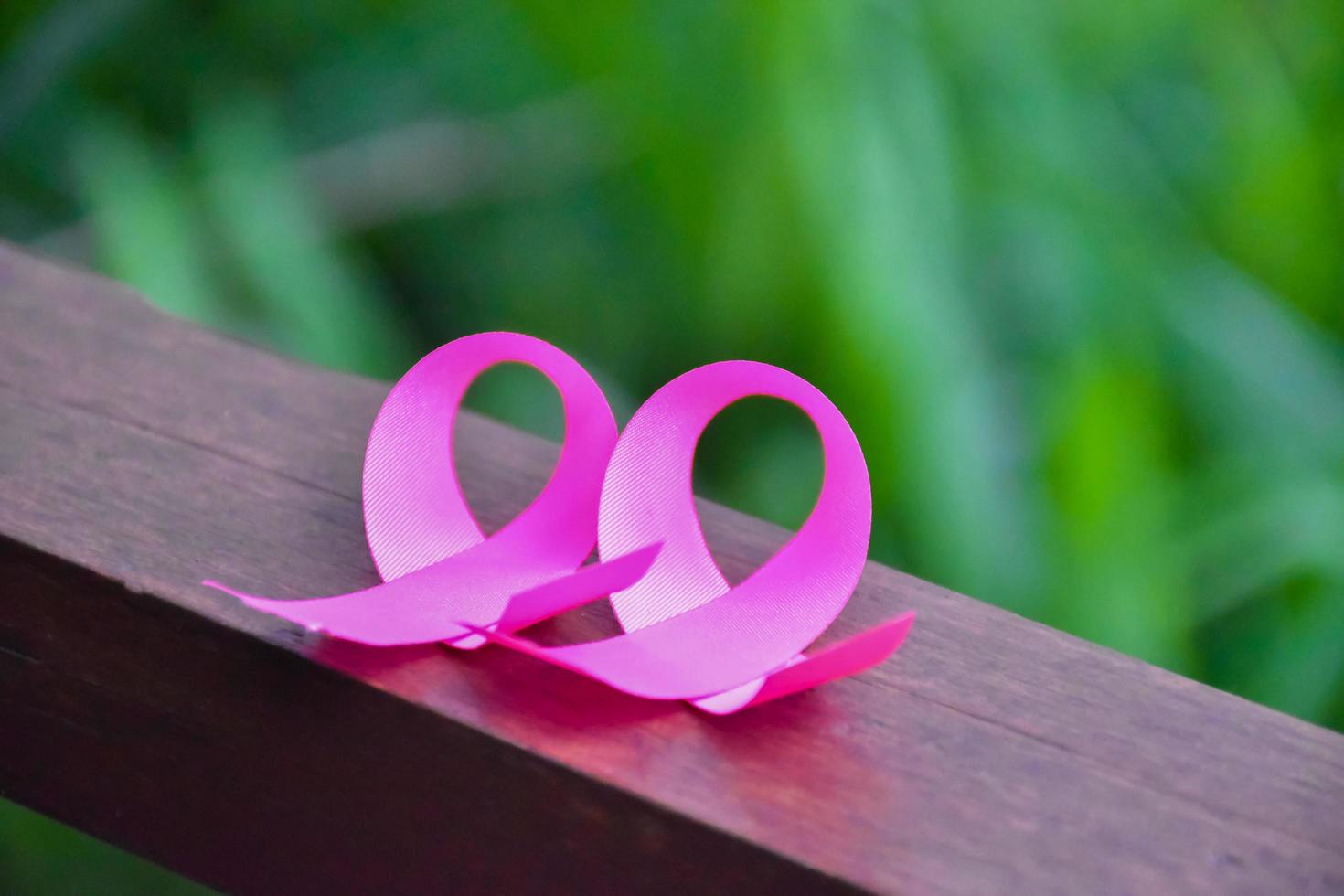 roze lint op houten tafel, concept voor de bestrijding van borstkanker bij vrouwen over de hele wereld. selectieve focus en kopieer ruimte. foto