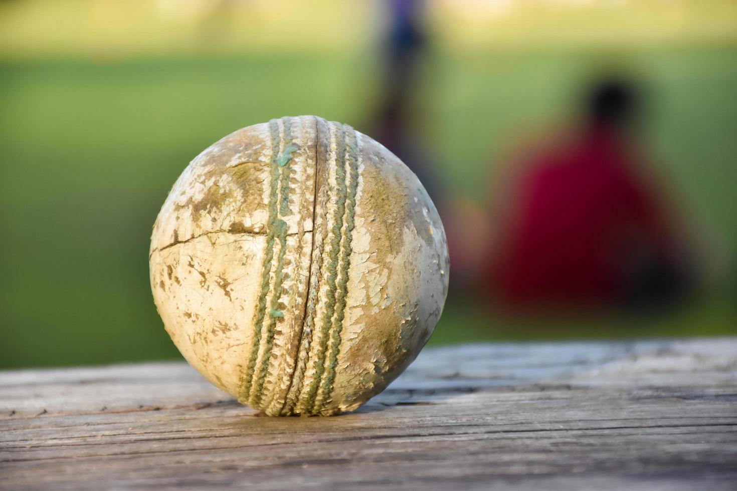 oude trainingscricket-sportuitrusting op donkere vloer, leren bal, wickets, helm en houten vleermuis, zachte en selectieve focus, traditionele cricketsportliefhebbers over de hele wereld. foto