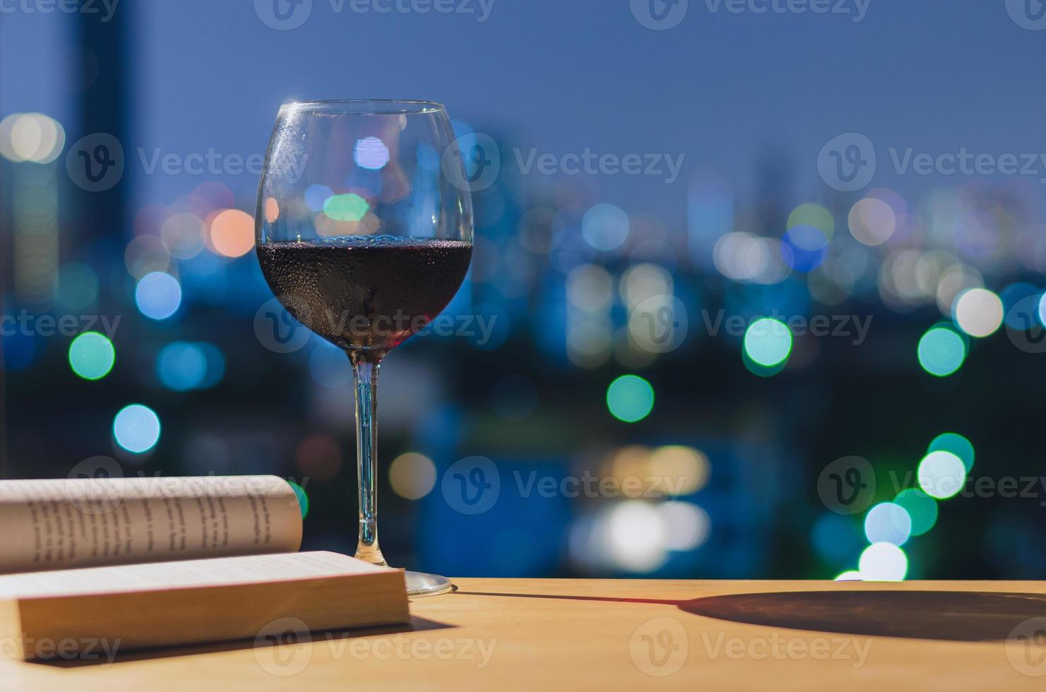 een glas rode wijn en boek op houten tafel. foto