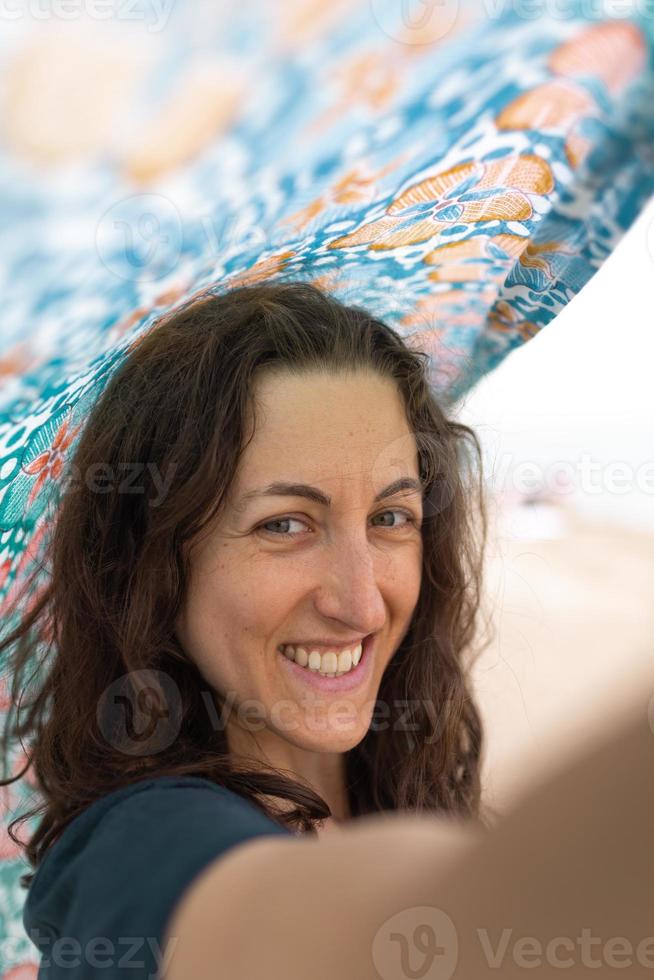 een vrouw houdt een hoofddoek over haar hoofd en de wind waait door haar sjaal foto