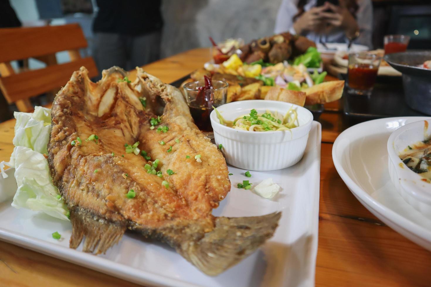 gefrituurde zeebaars met vissaus en pittige zeevruchtensaus is een populair gerecht bij visrestaurants die vanwege de heerlijke smaak vaak een menukaart hebben van gefrituurde zeebaars met vissaus. foto