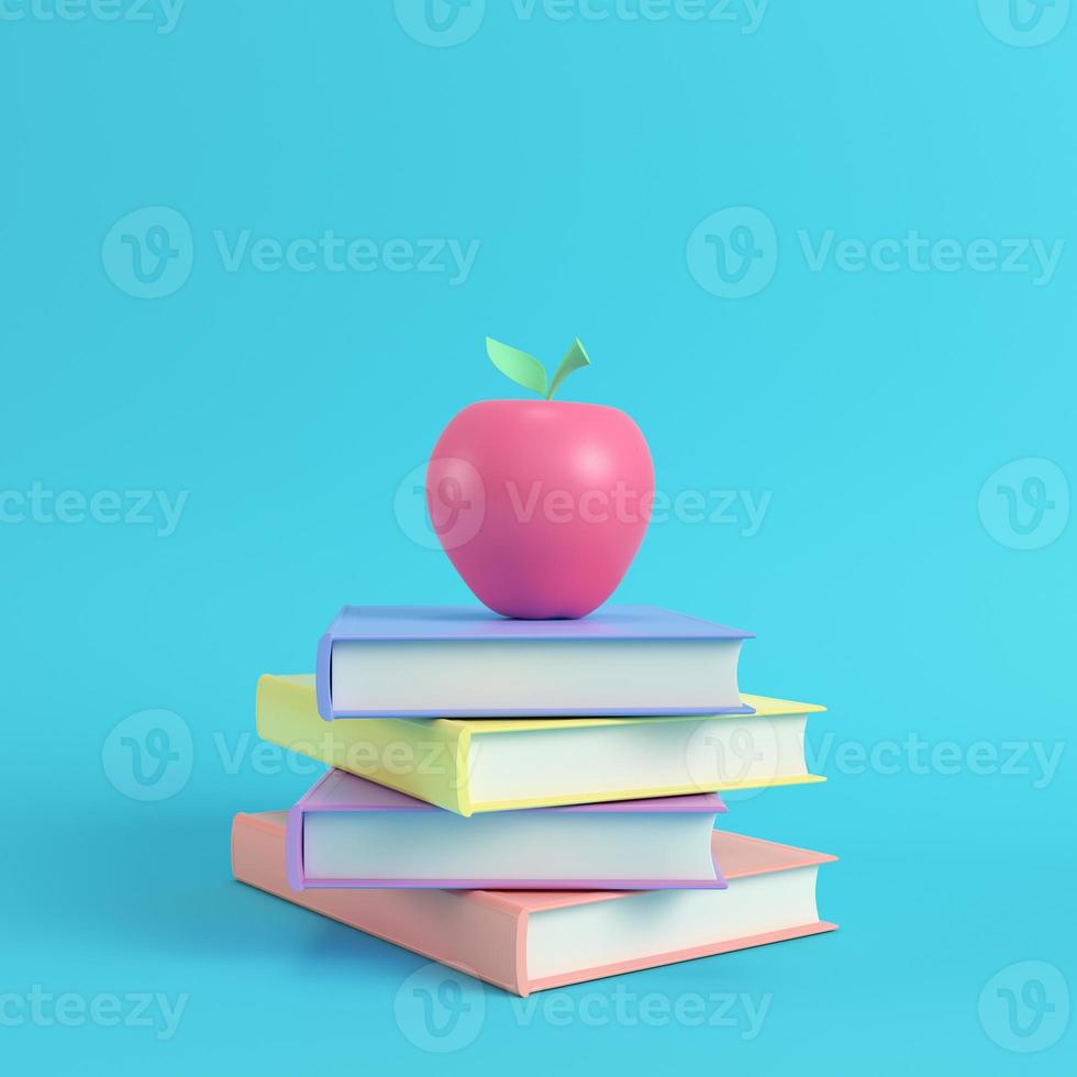 roze appel op een stapel boeken op felblauwe achtergrond in pastelkleuren foto