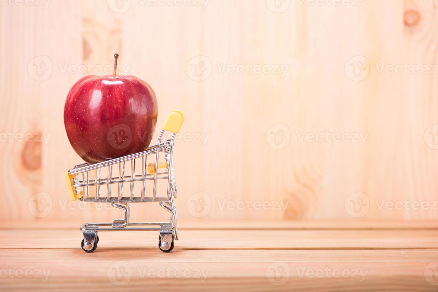 appelrood op winkelwagentje met houten vloer achtergrond foto