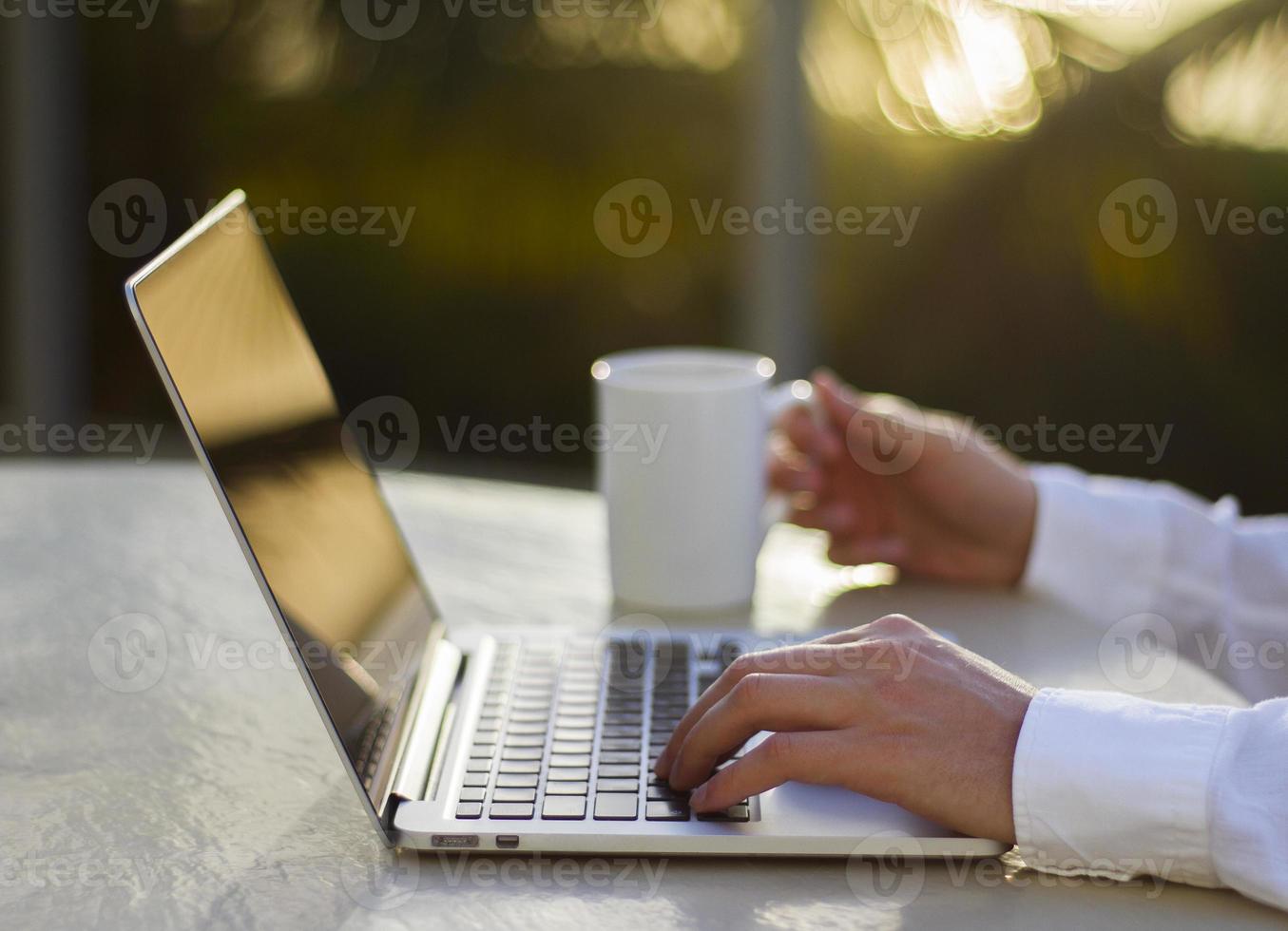 zakenman werken met laptop en kopje koffie bij zonsondergang foto