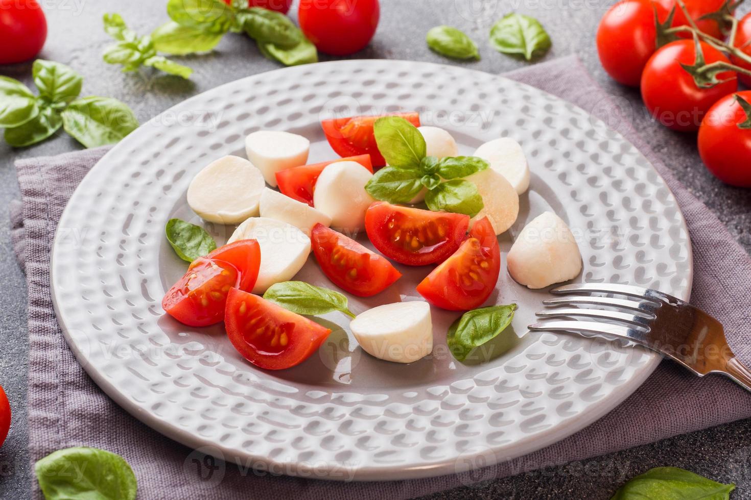 Caprese salade van tomaten, mozzarella kaas en basilicum op een donkere achtergrond. Italiaanse keuken. foto