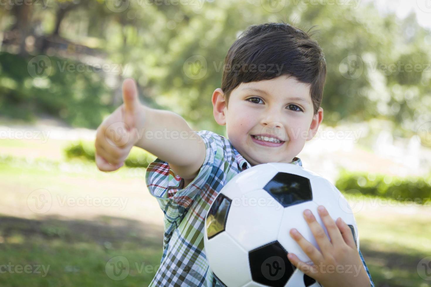 schattige jonge jongen spelen met voetbal in park foto