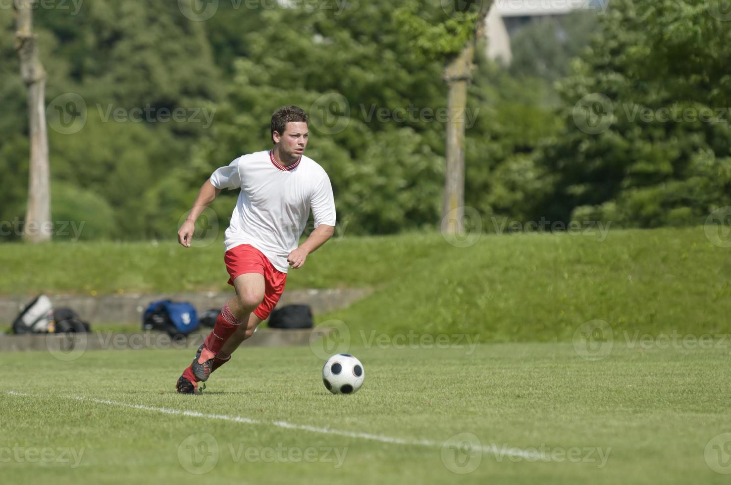 een mannelijke voetballer dribbelt de bal over het veld foto