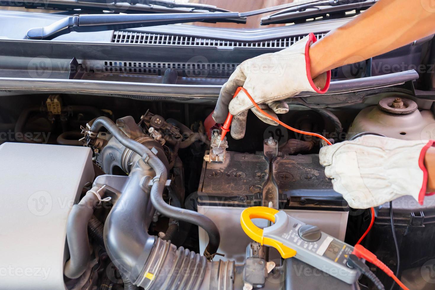 automonteur bezig met automotor controleren batterij in mechanica garage, reparatie en onderhoudsservice foto
