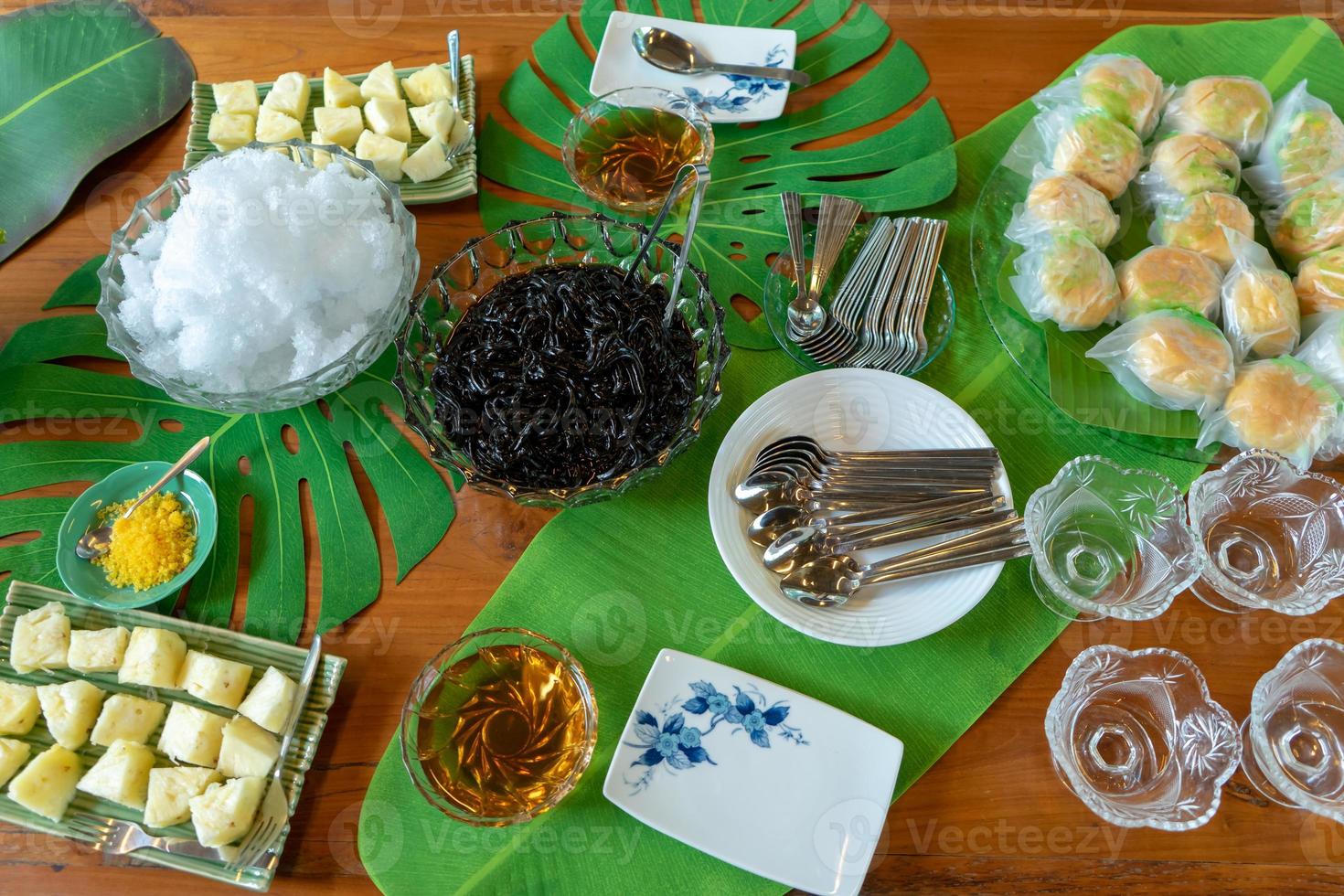 gemengd dessert in high tea break ananasbroodroom en ijszwarte gelei met siroop op decoratieblad op houten tafel. foto