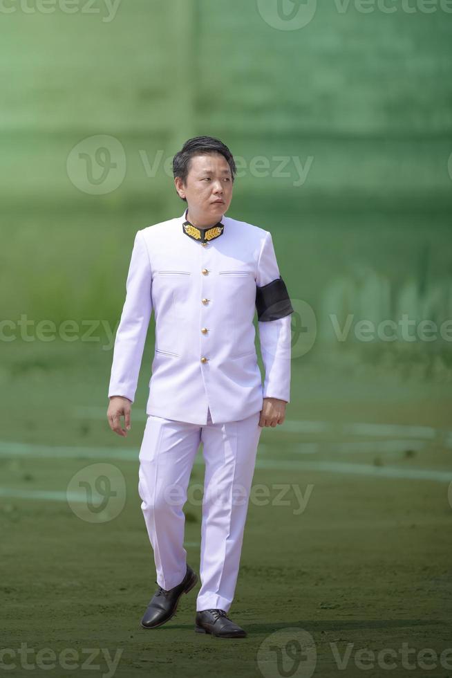 aziatische thaise man kleedt het witte formele pak voor het belangrijke overheidsevenement met groene achtergrond. foto