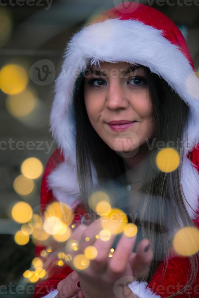 een kerstvrouw met een ketting van lichtjes in haar hand foto