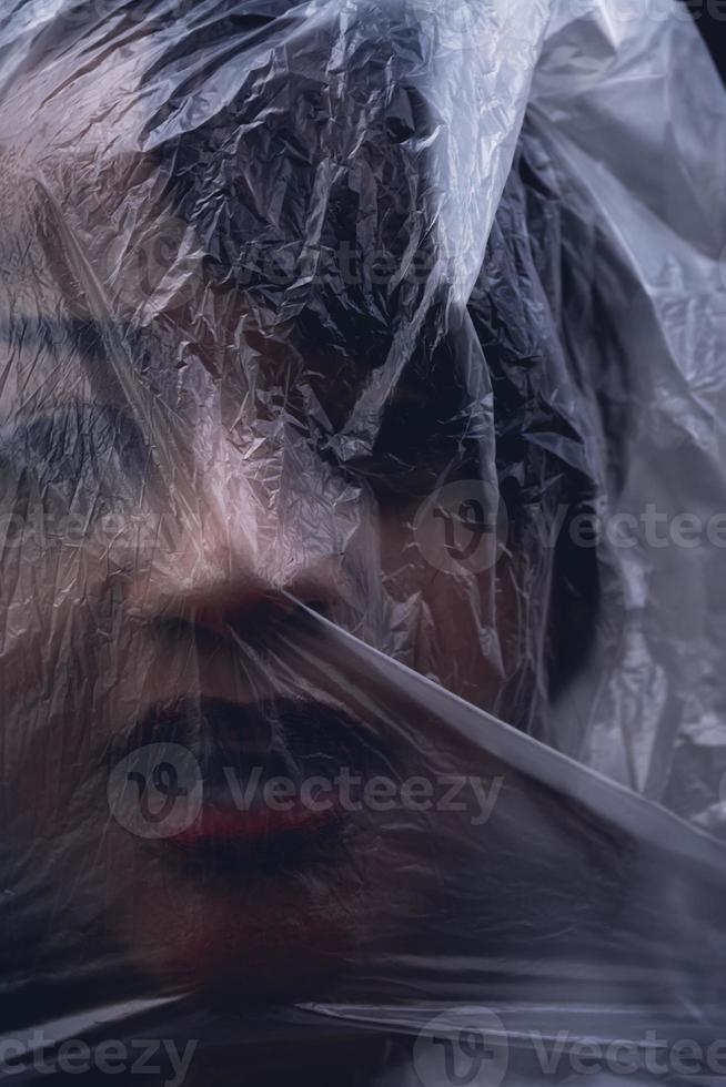vrouw met haar gezicht bedekt met een plastic vel foto