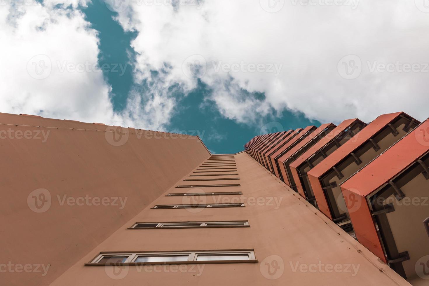 een hoogbouw met kleine rode balkons met uitzicht van onderen foto