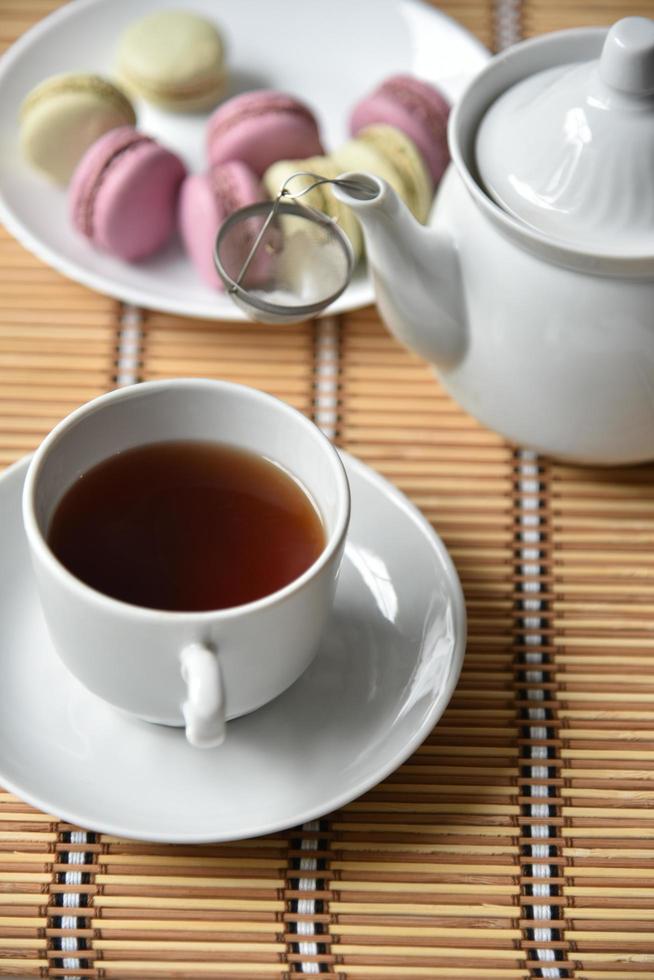 porseleinen theepot met een kopje thee en bitterkoekjes foto