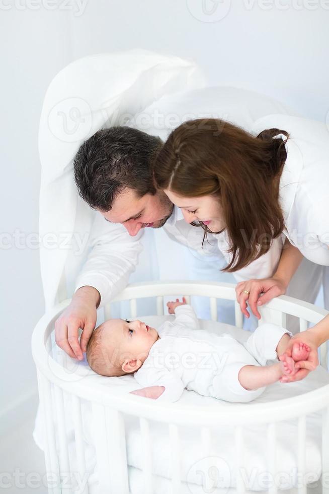 gelukkige ouder die babyzoon in witte ronde wieg bekijkt foto
