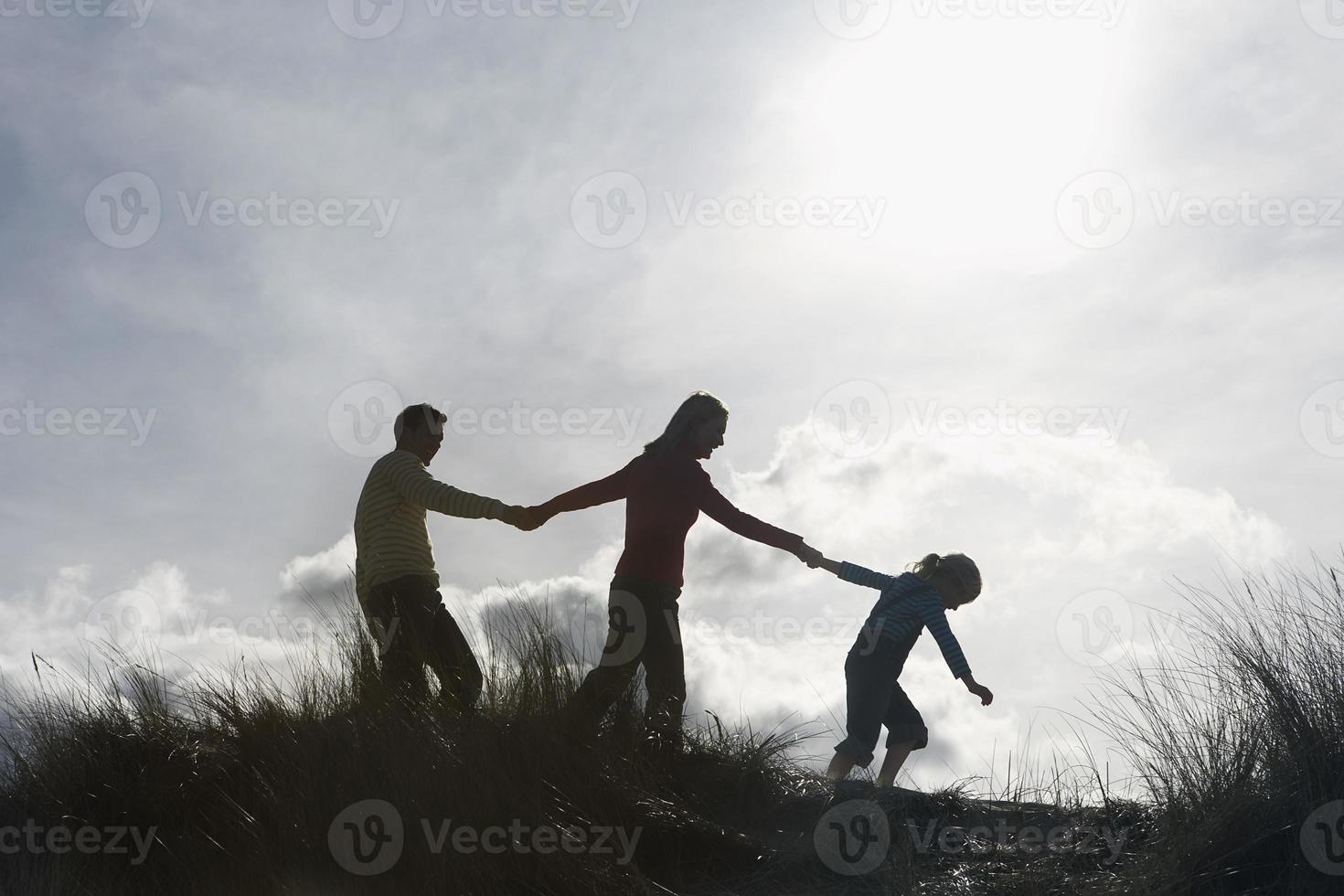 familie hand in hand tijdens het wandelen op het strand foto