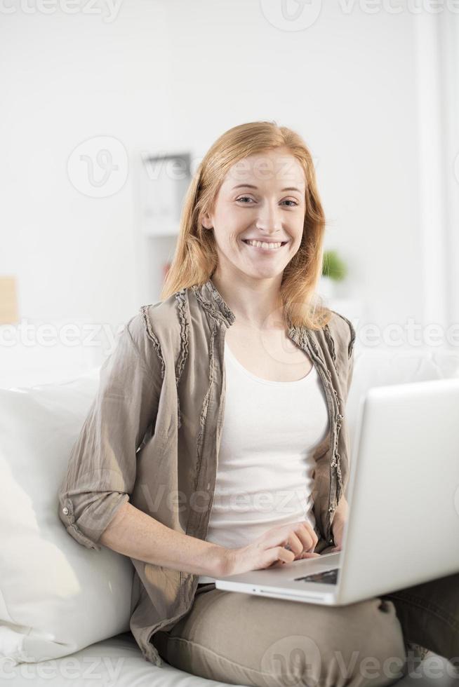 jonge vrouw gelukkig met behulp van laptop op Bank foto