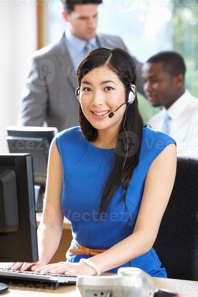 zakenvrouw dragen hoofdtelefoon werken in drukke kantoor foto