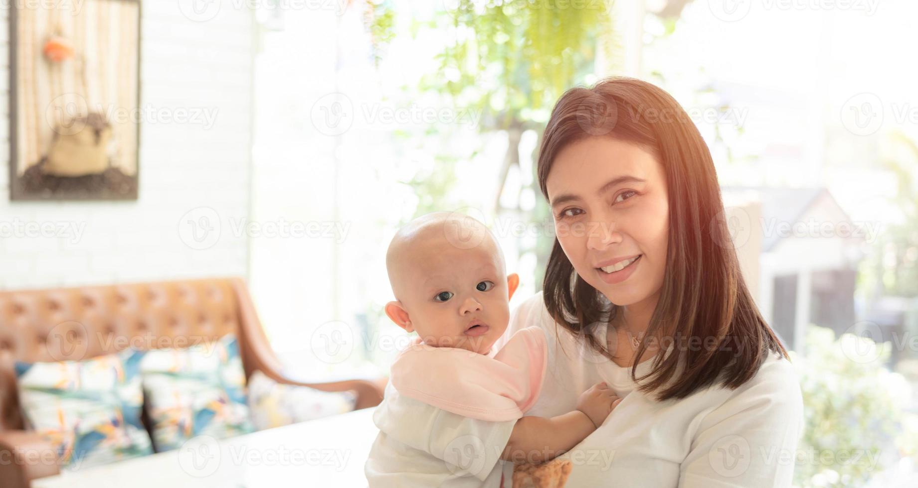 gelukkige familie, schattige Aziatische pasgeboren baby met jonge moeder glimlach blij gezicht. onschuldige kleine baby schattig. moeder draagt, zorgt met liefde voor binnenshuis. ouderschap, moederdagconcept. foto