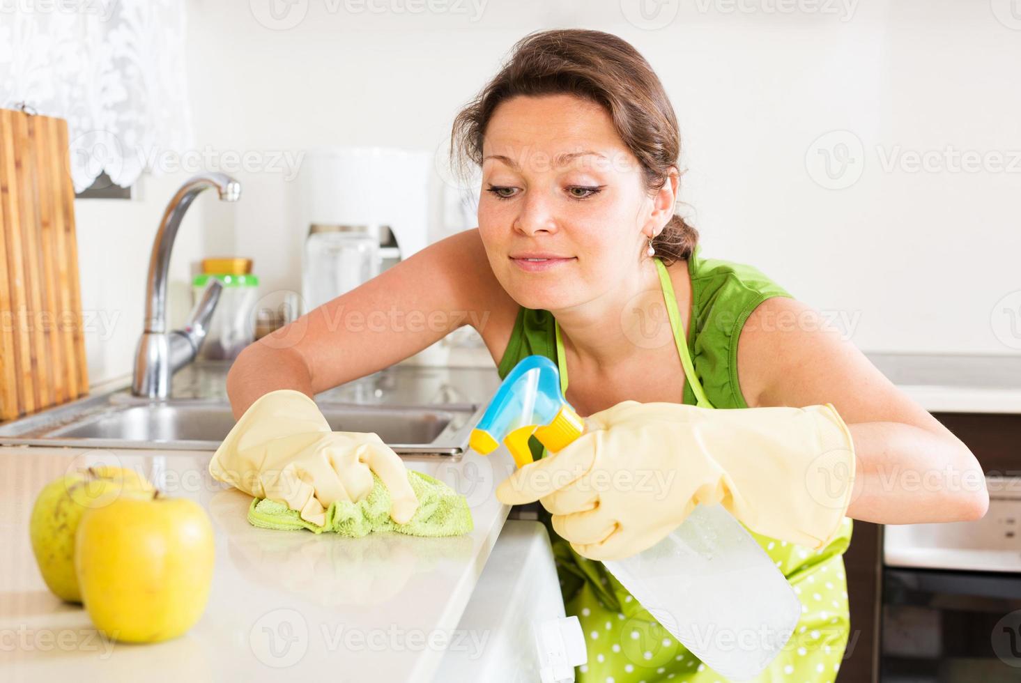 huisvrouw het schoonmaken van meubilair in keuken foto