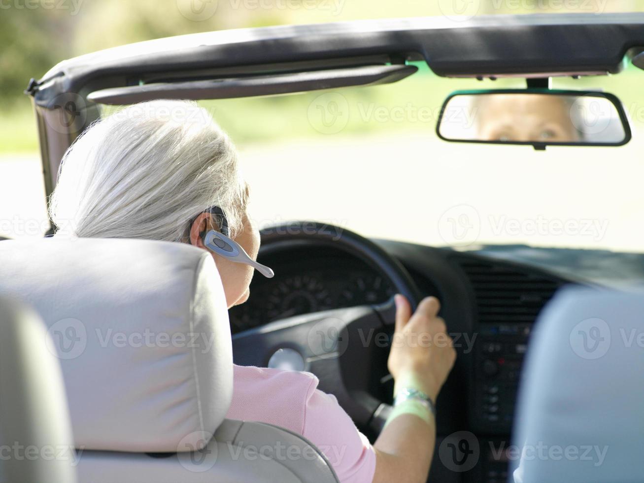 vrouw met handsfree-apparaat in de auto, achteraanzicht foto