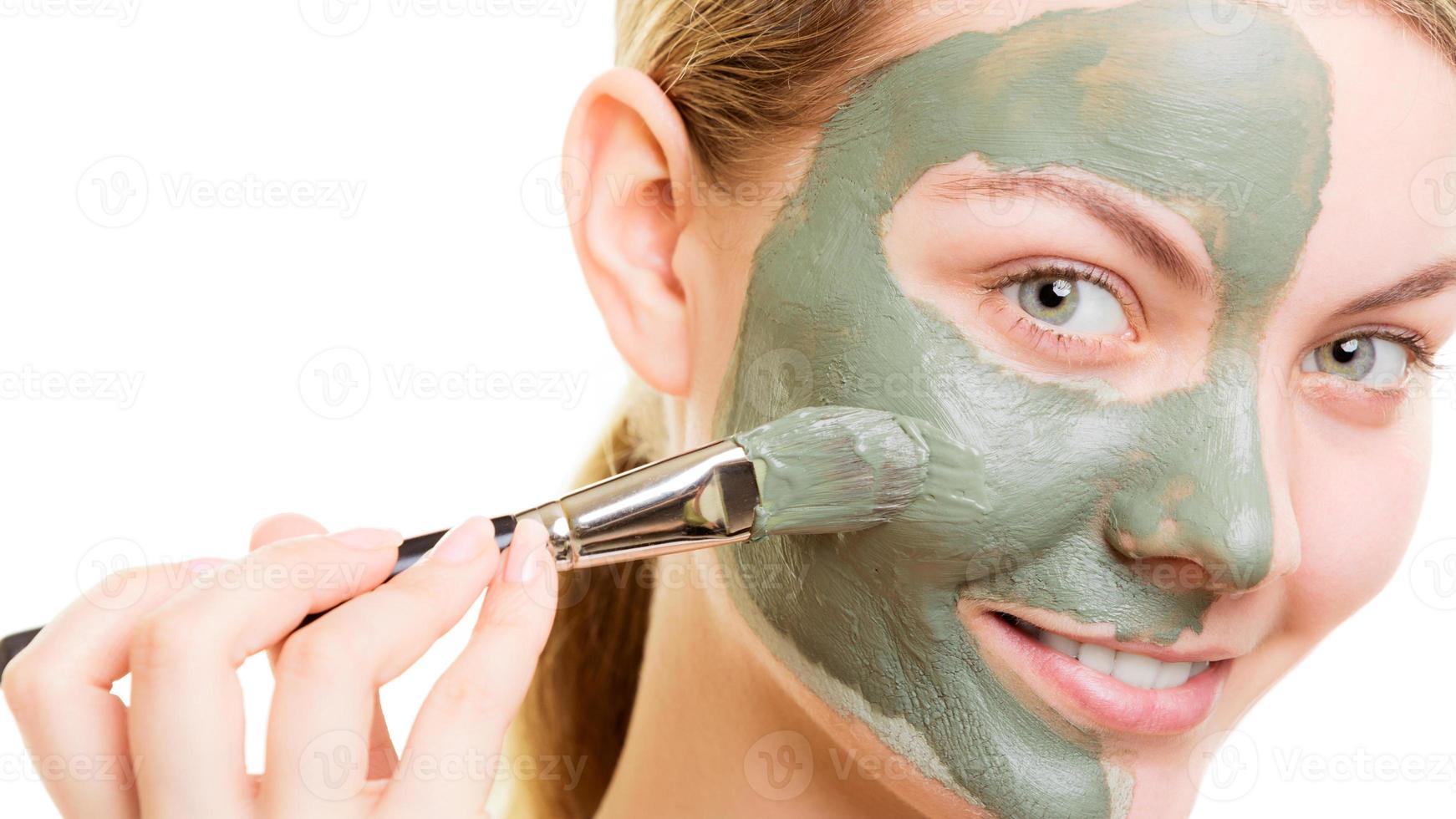 vrouw toepassing met kwast klei modder masker haar gezicht foto