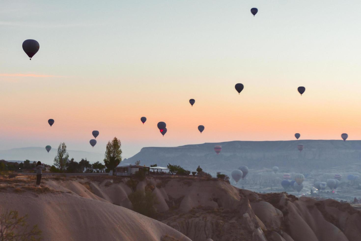 jong kaukasisch romantisch koppel zit en geniet van ballonnen in de lucht op zonnige ochtend bij zonsopgang tijdens het kamperen .travel cappadocia ontspannende vakantiebestemming foto