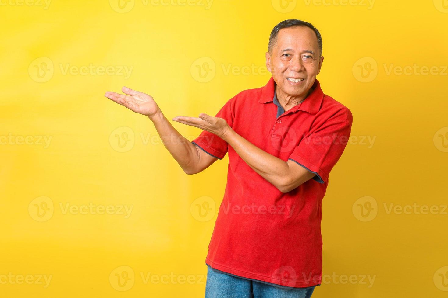 portret van vrolijke aziatische gepensioneerde oude man draagt een rood t-shirt, wijzende handen of presenteren. foto