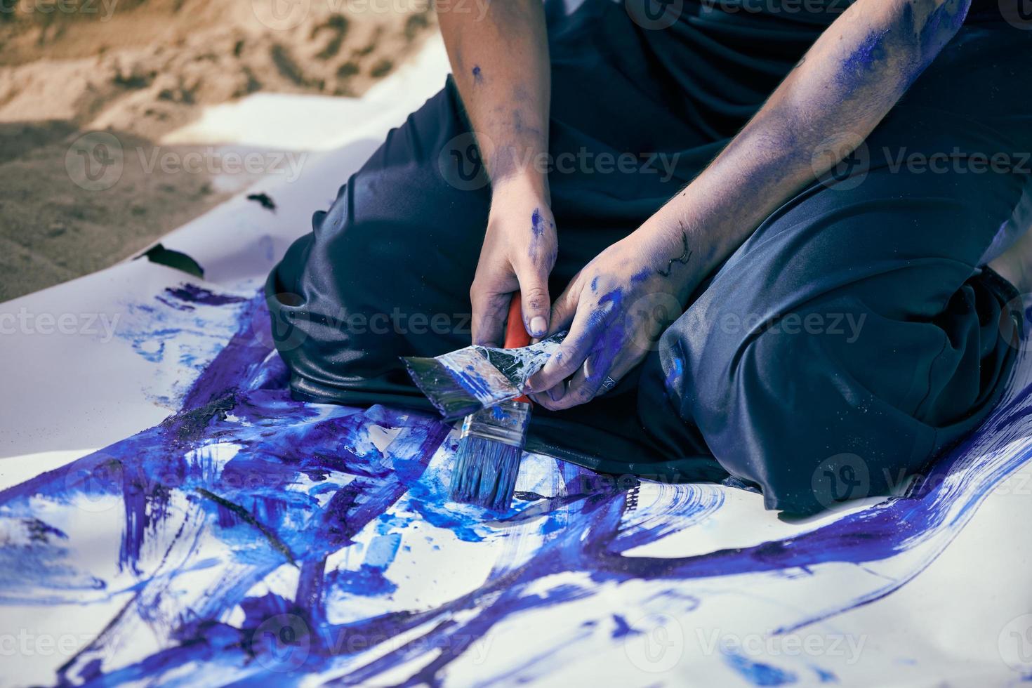 vrouwelijke performancekunstenaar in donkerblauwe jurk besmeurd met blauwe gouache-schilderij met brede streken op canvas foto