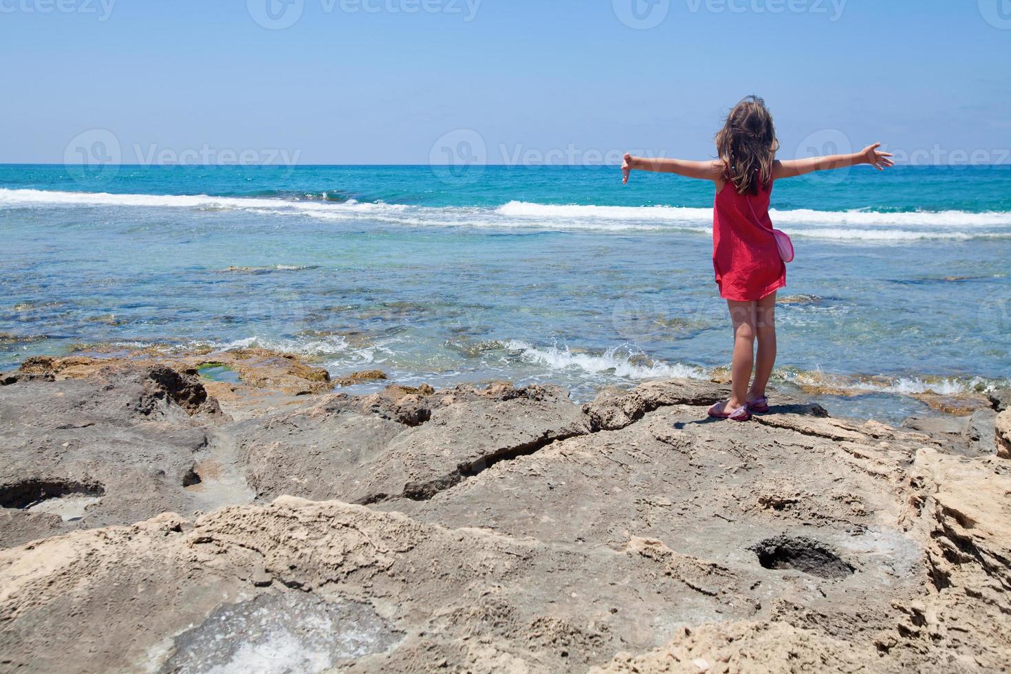 klein meisje genieten in een wind van tha zee foto