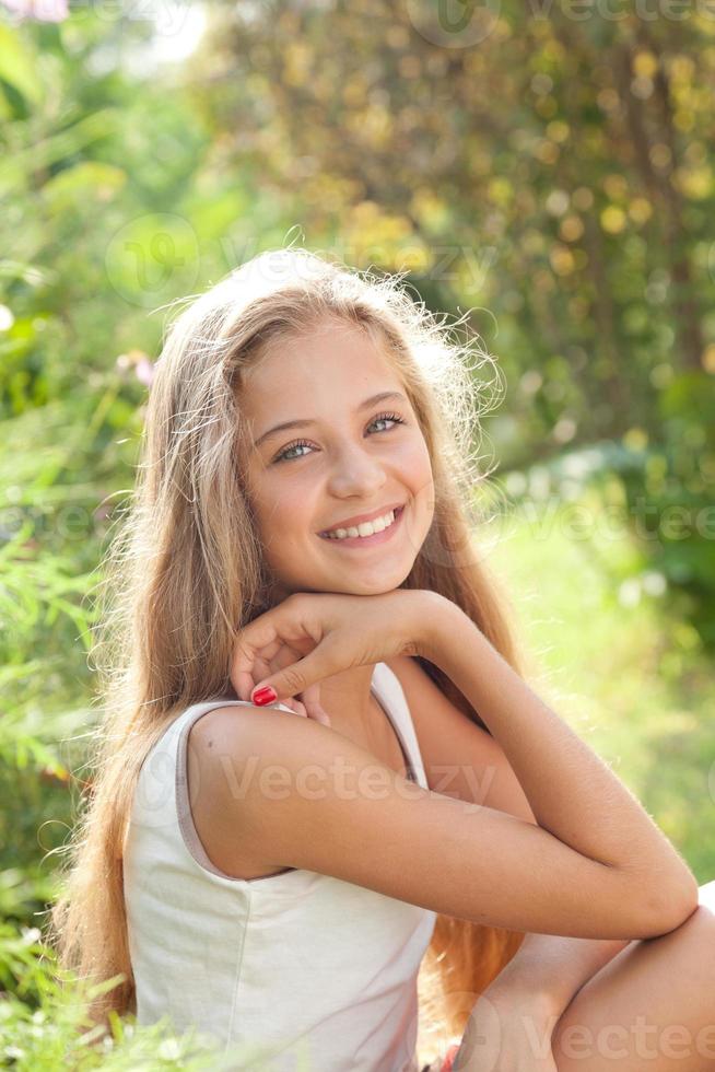 portret van mooie tienermeisje zitten, glimlachen, genieten van de natuur foto