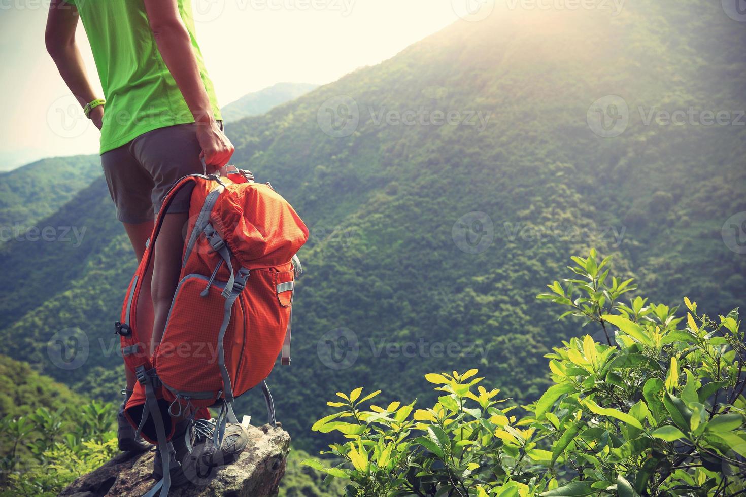 vrouw backpacker geniet van het uitzicht op de bergtop klif foto